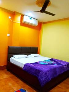 プリーにあるGoroomgo Sahoo Palace Puri Near Sea Beachのベッドルーム(紫の毛布付きのベッド1台付)