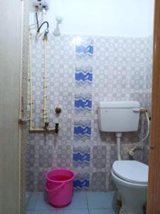 a bathroom with a toilet and a pink bucket at Goroomgo Sahoo Palace Puri Near Sea Beach in Puri