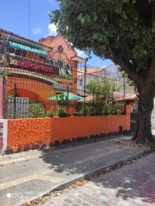 uma cerca laranja com uma árvore em frente a um edifício em Pousada San Salvador em Salvador