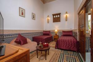 sala de estar con muebles de color rojo y TV en Riad Myra, en Fez