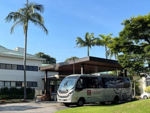 un autobús estacionado frente a un edificio con palmeras en Hotel Panamby Guarulhos en Guarulhos