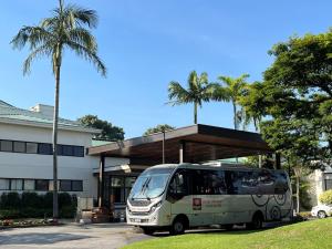 a bus parked in front of a building with palm trees at Hotel Panamby Guarulhos in Guarulhos