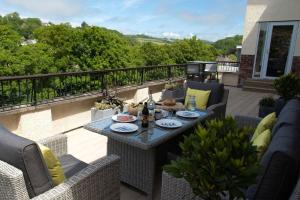 a patio with a table and chairs on a balcony at Tylecroft in Noss Mayo