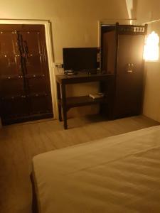 - une chambre avec un lit et un bureau avec une télévision dans l'établissement Chhoti Kothi - A Heritage Homestay by the Ganges, à Prayagraj