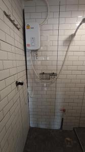 a shower in a bathroom with white tiled walls at Chubby 9 Room 7 in Ban Bang Phlat