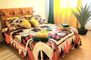 a bed with a colorful comforter and towels on it at L'Harmonie de Naya, confort , parking privé in Bourges