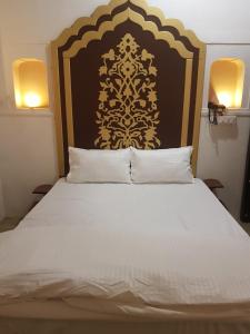 a bedroom with a large bed with a black and gold headboard at Chhoti Kothi - A Heritage Homestay by the Ganges in Prayagraj