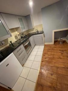 a kitchen with white cabinets and a wooden floor at Mezz Apartment Four in Hull