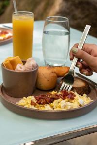 a plate of breakfast food with a fork and a glass of orange juice at Cacaoni Hotel in Puerto Colombia