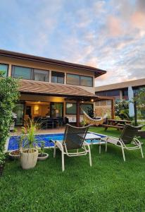 ein Haus mit zwei Stühlen und einem Pool in der Unterkunft Casa Luxo com piscina privativa próximo a Igrejinha - Com colaboradora e enxoval in Praia dos Carneiros