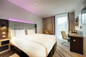 a hotel room with a large bed and a desk at Premier Inn Köln City Mediapark in Cologne