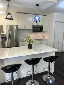 a kitchen with a large white counter with bar stools at Villa Maria in Port-of-Spain