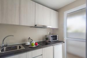 uma cozinha com armários brancos, um lavatório e um micro-ondas em Playa Park Zensation em Corralejo