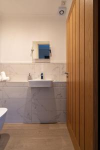 a white bathroom with a sink and a mirror at Steels cross House in Lanark