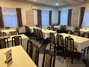uma sala cheia de mesas e cadeiras com toalhas de mesa brancas em Apartmani Ristanović Užice em Užice