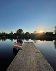un muelle con un barco en el agua al atardecer en Big villa by the lake en Olofström
