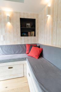 a small room with a bed with a red pillow at Tiny house avec vue sur les étoiles in Jalhay