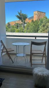 stół i 2 krzesła na balkonie z oknem w obiekcie Comodo y acogedor departamento w mieście Puerto Montt