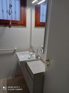 ein weißes Badezimmer mit einem Waschbecken und einem Spiegel in der Unterkunft Stintino vista mare in Stintino