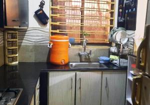 um recipiente laranja sentado num balcão de cozinha ao lado de um lavatório em Room Stylish 1BHK em Islamabad