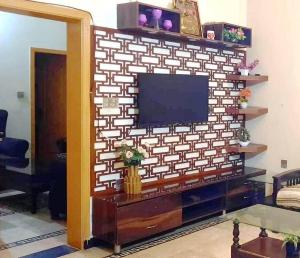 uma sala de estar com televisão numa parede de tijolos em Room Stylish 1BHK em Islamabad