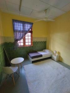 a room with a bed and a table and a window at Inapan Salsabila in Jitra