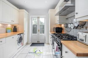 a kitchen with white cabinets and a stove top oven at Beautiful 3 BDR House in Windsor Town By Sentinel Living Short Lets & Serviced Accommodation Windsor Ascot Maidenhead With Pet Friendly & Superfast Wifi in Windsor