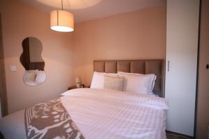Adora's Apartment Mavrovo في مافروفو: غرفة نوم بسرير كبير مع شراشف بيضاء