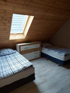 a attic bedroom with two beds and a window at Domki u Justyny in Podgórzyn