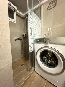 een wasmachine in een badkamer met een douche bij KOI Apartment Toumba SKG in Thessaloniki