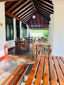 eine Terrasse mit Holzbänken, Tischen und Stühlen in der Unterkunft Sadamadala Guest House Kandy in Kandy