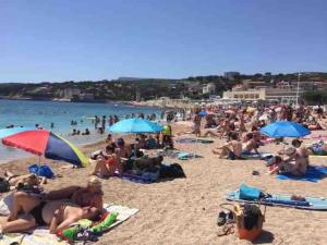 a crowd of people on a beach with umbrellas at Grand appartement a 5 minutes du stade vélodrome, parking in Marseille