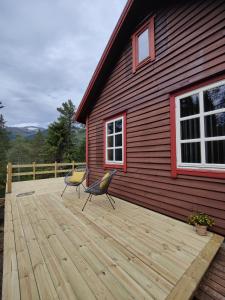 - une terrasse en bois avec 2 chaises au-dessus d'une maison dans l'établissement Tronstadbu- Traditional cabin, à Hellesylt