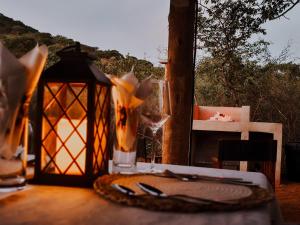 a table with a lantern and a plate and a glass at Mountain Peak Game Lodge and Camping in Outjo