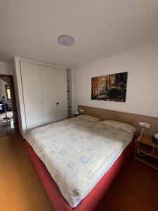 1 dormitorio con 1 cama y una pintura en la pared en Appartamento per Famiglie, 6 posti, in centro ad Asiago, en Asiago