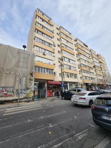 un grande edificio con macchine parcheggiate di fronte di Victoriei Elite Apartments-Free Minibar a Bucarest
