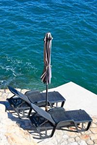 two chairs and an umbrella next to the water at Apartment First Row in Komarna