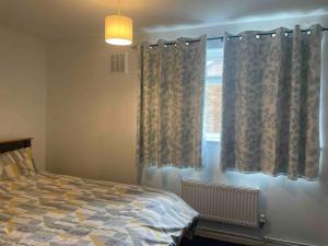 a bedroom with a bed and a window with curtains at Stylish 2 bedroom house Edgware, Barnet in Hendon