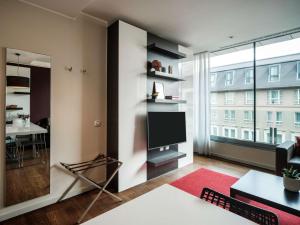 a living room with a tv and a large window at NH Collection Budapest City Center in Budapest