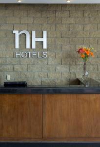 a hotel sign on a brick wall with a vase of flowers at NH Antofagasta in Antofagasta
