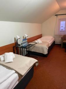 Una habitación con 2 camas y una mesa con botellas. en Hotel SONATA en Duszniki Zdrój