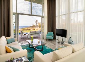 a living room with white furniture and a view of the ocean at Le Meridien Bodrum Beach Resort in Bogazici