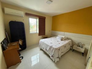 a bedroom with a bed and a desk and a television at Apartamento em Icaraí - 2 suítes in Caucaia