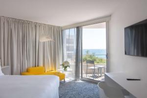 Cette chambre d'hôtel dispose d'une chaise jaune et d'une grande fenêtre. dans l'établissement nhow Marseille, à Marseille