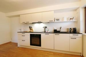 una cucina con armadi bianchi e forno nero di Tannenhof Fischbach - Fewo 1 "Felchen" - Schluchsee, 2 Schlafzimmer a Schluchsee