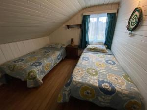 2 camas en una habitación pequeña con ventana en Hospedaje Nehuen Karu, en Puerto Varas