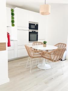 une cuisine avec des placards blancs et une table et des chaises blanches dans l'établissement Carvoeiro Beach Appartment, à Carvoeiro