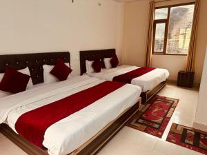2 letti con lenzuola rosse e bianche in una camera da letto di The Asha Residency - Majestic Mountain View , Shimla a Shimla