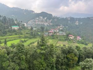 uma cidade numa colina com árvores e edifícios em The Asha Residency - Majestic Mountain View , Shimla em Shimla