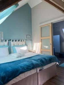 1 dormitorio con 1 cama grande con manta azul en Au Domaine de Sophie piscine chauffée couverte et jacuzzi couvert, en Crasville